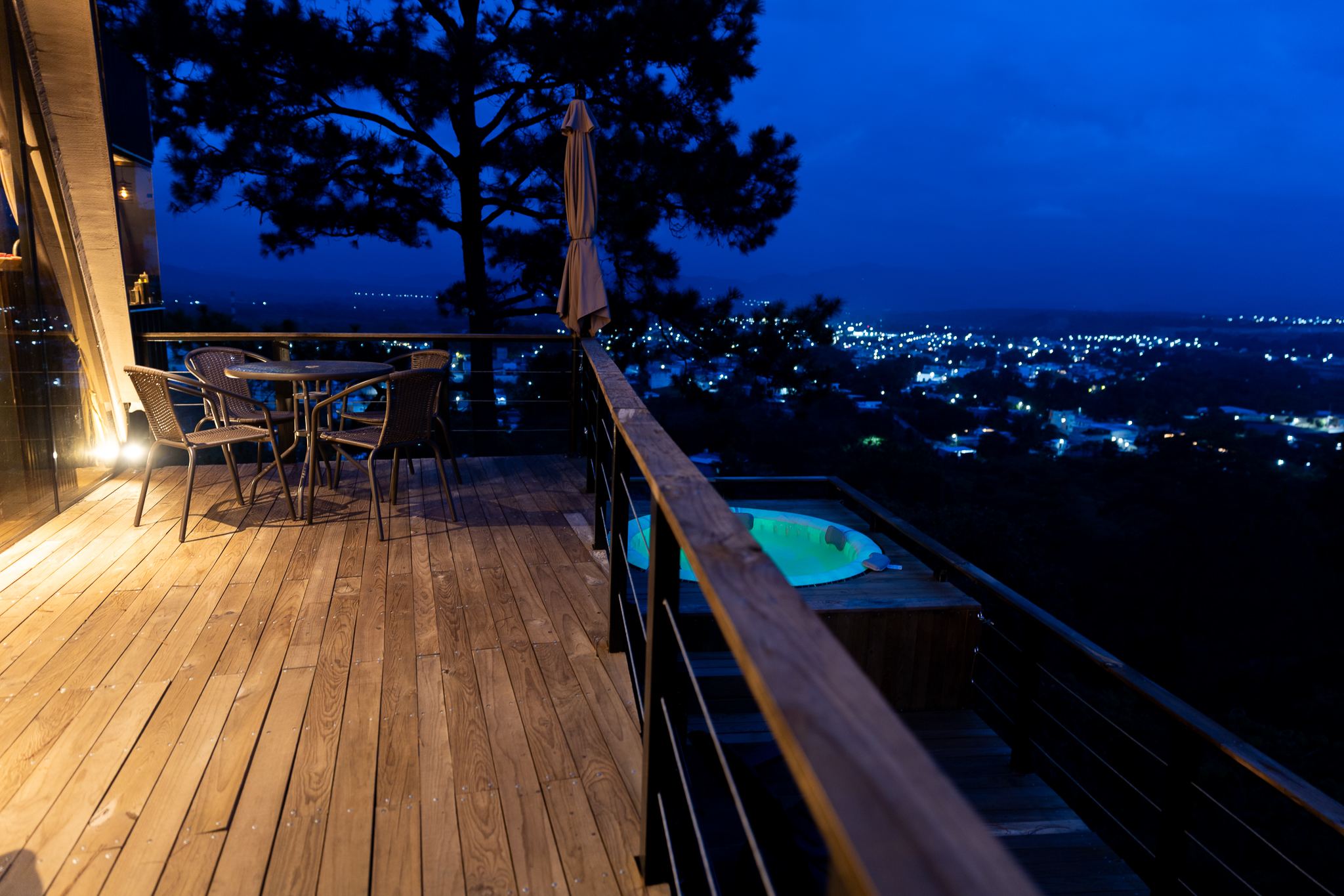 Mesa para dos en el deck junto al jacuzzi, con la ciudad iluminada de noche