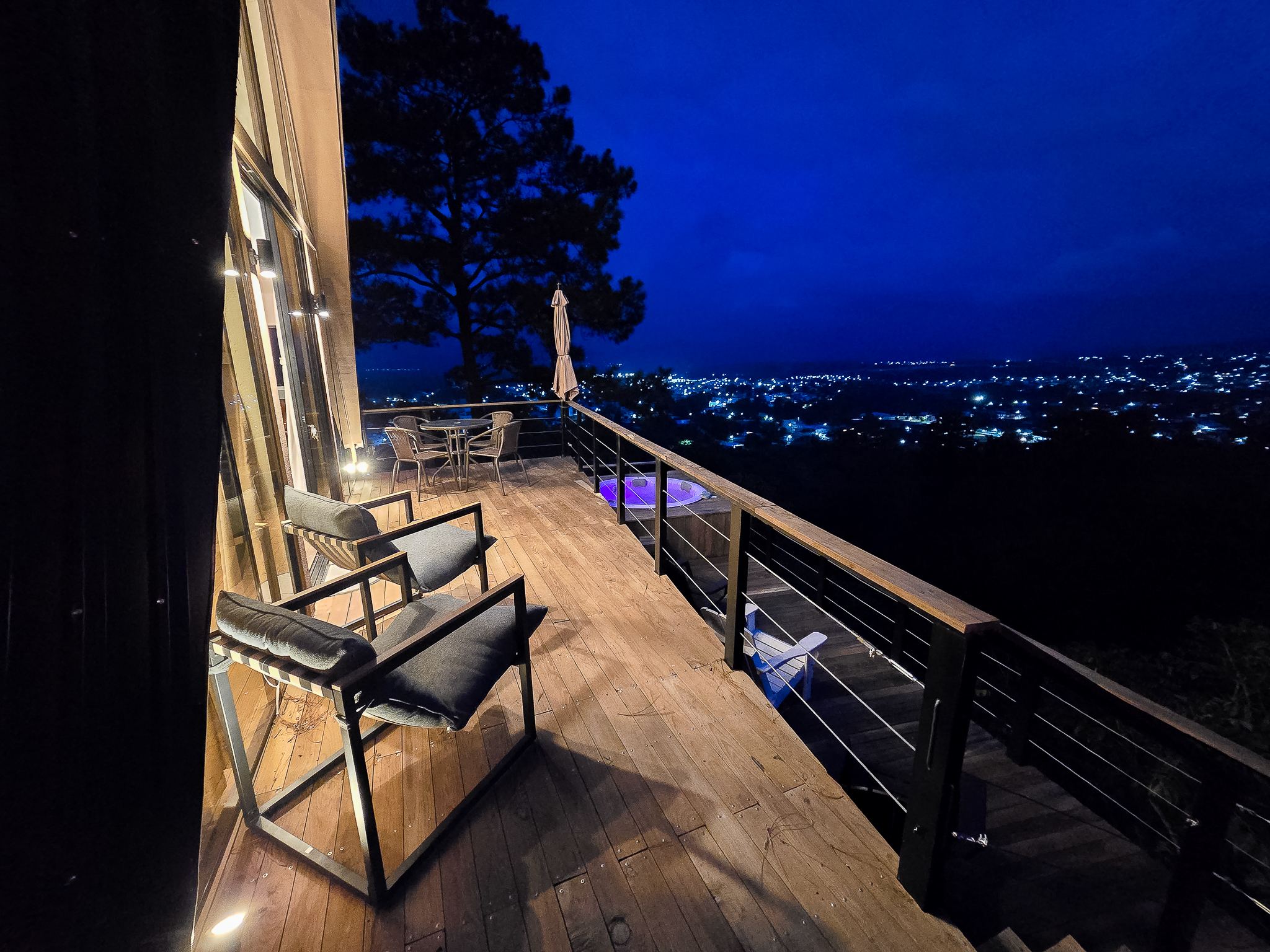 Deck de la cabaña de noche con sillas y la ciudad de Esquipulas iluminada al fondo
