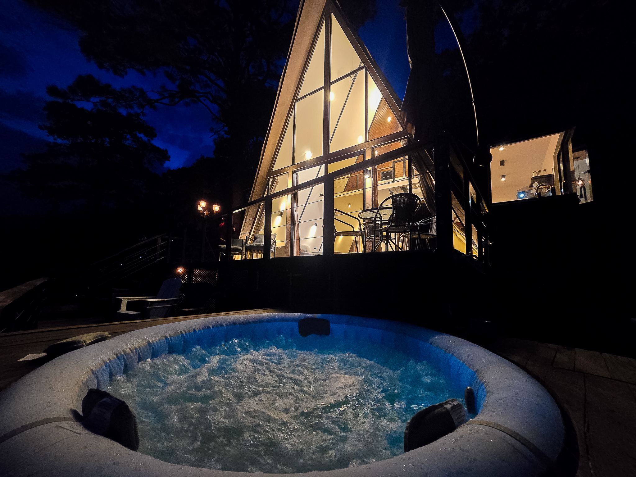 Jacuzzi en burbujas frente a la cabaña iluminada de noche